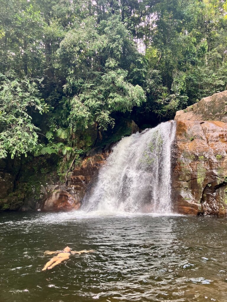Sinharaja Rain Forest, a woman floating in a lake with a waterfall