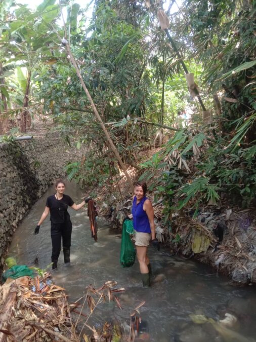Two ladies getting dirty during a river clean-up with Sungai Watch